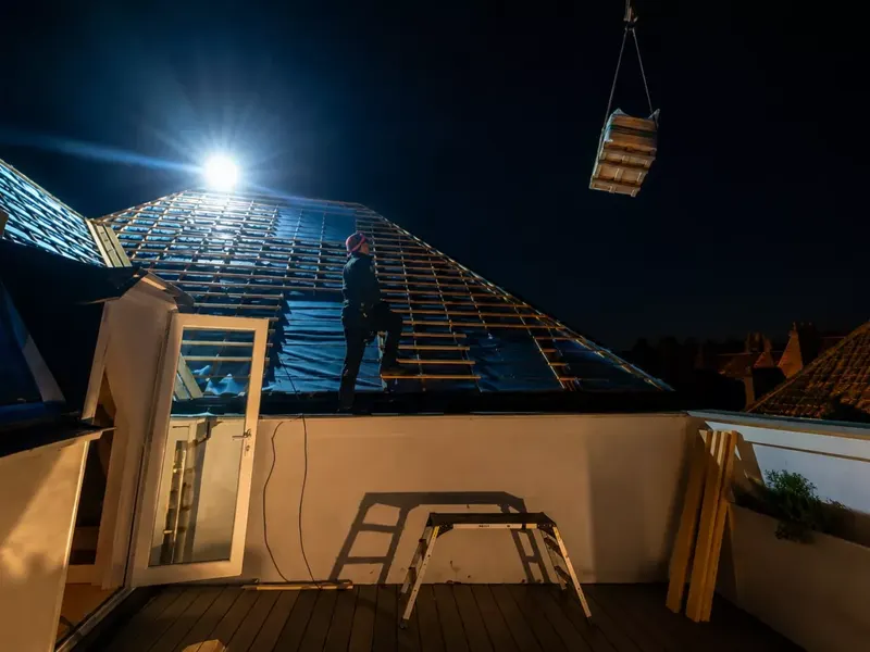 Intervention sur toiture de nuit, sous éclairage de chantier